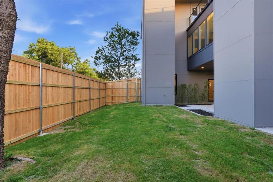 Expansive lawn area enclosed by a wood privacy fence