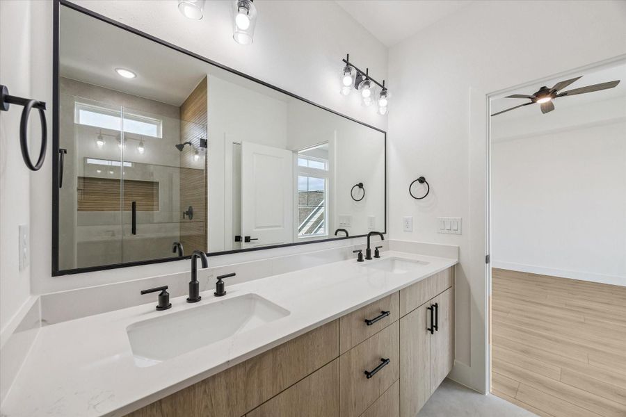 Dual vanity bath with wood cabinetry, framed mirrors, and upgraded lighting Dual vanity bath with wood cabinetry, framed mirrors, and upgraded lighting