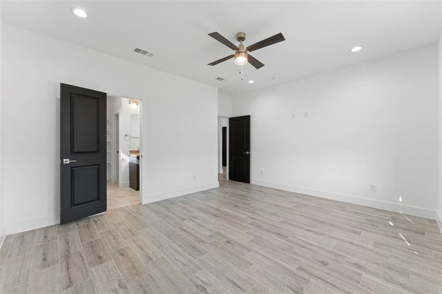 Unfurnished bedroom featuring ceiling fan, connected bathroom, and light hardwood / wood-style flooring