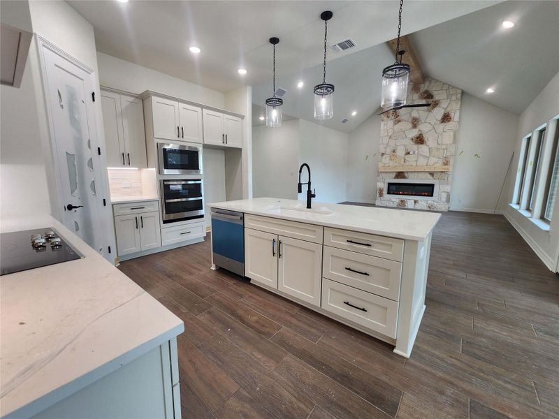Kitchen island with an undermount sink, a matte black faucet, and pendant lighting