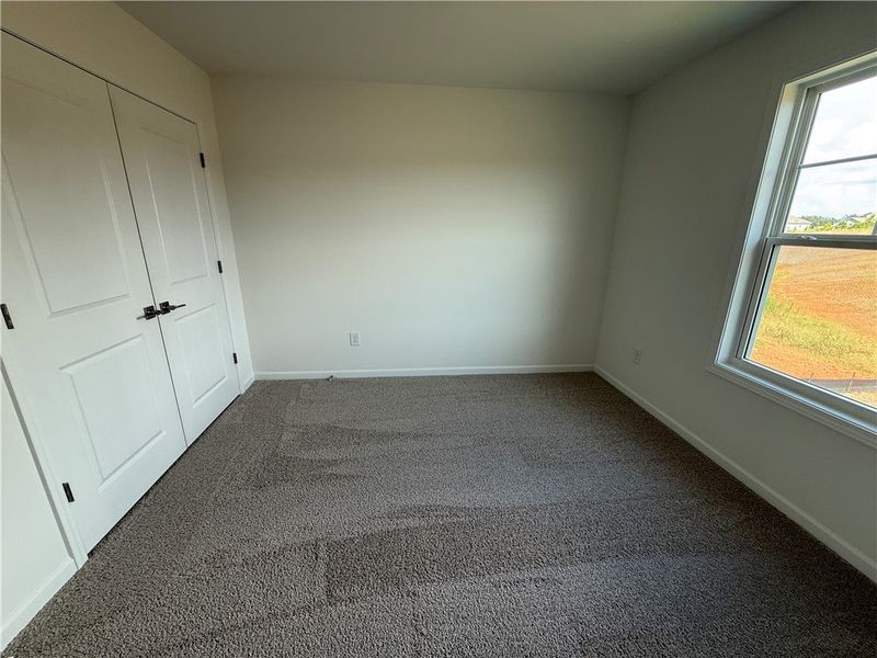 A well-lit bedroom features plush carpeting and am A well-lit bedroom features plush carpeting and am
