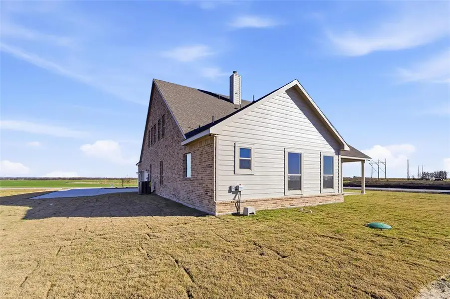 View of side of property with a chimney, brick siding, and a yard