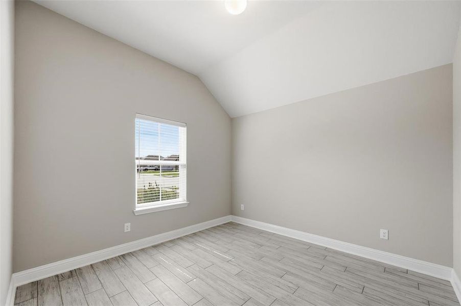 Unfurnished room featuring lofted ceiling and wood tiled floors Unfurnished room featuring lofted ceiling and wood tiled floors