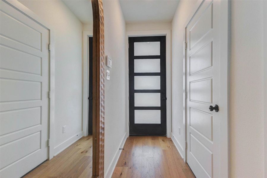 Step into a clean, modern entry that sets the tone for the entire home. This welcoming foyer features warm wood flooring, crisp white walls, and a striking contemporary front door with frosted glass panels that allow natural light to flow in while maintaining privacy. Sleek trim details and a minimalist design create a fresh, upscale first impression that immediately feels inviting and refined. The picture shown is from the model home with the same floor plan, Rev floor plan.