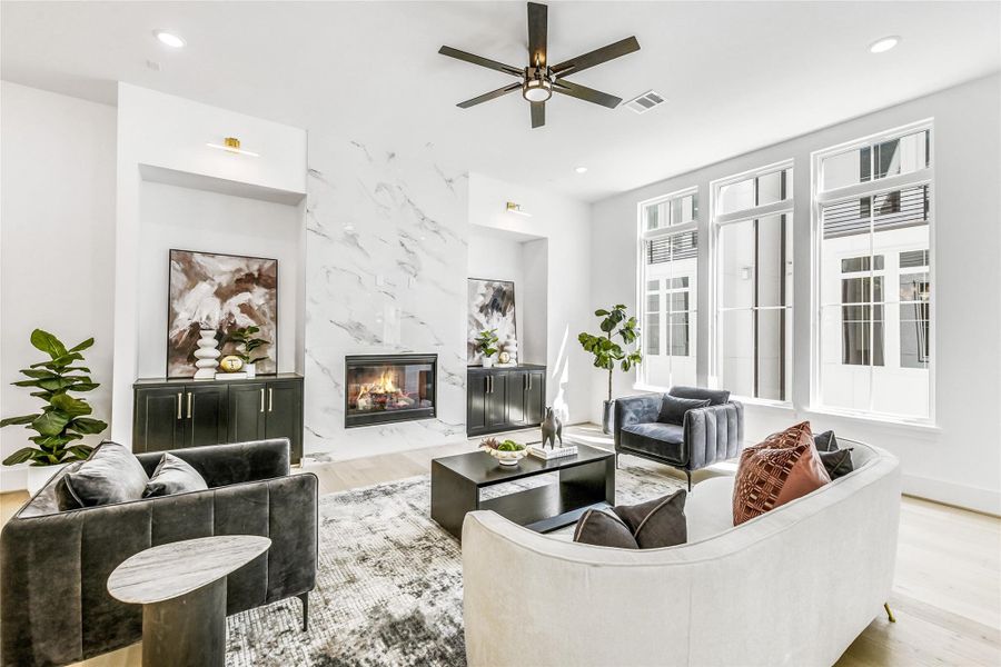 A stunning floor-to-ceiling porcelain fireplace serves as the centerpiece of this luxurious living area. Flanked by custom built-in cabinetry with brass hardware, the space blends form and function effortlessly. Designed for the refined professional, this room is perfect for entertaining guests or unwinding after long hours at the Texas Medical Center or Downtown Houston.