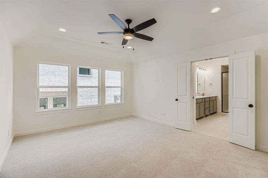 Unfurnished bedroom with light colored carpet, lofted ceiling, recessed lighting, ensuite bathroom, and a ceiling fan