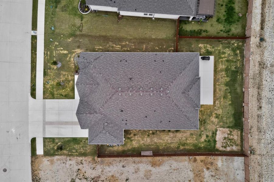 Property featuring a shingle roof, concrete driveway, concrete sidewalk, fenced perimeter, and established landscaping Property featuring a shingle roof, concrete driveway, concrete sidewalk, fenced perimeter, and established landscaping