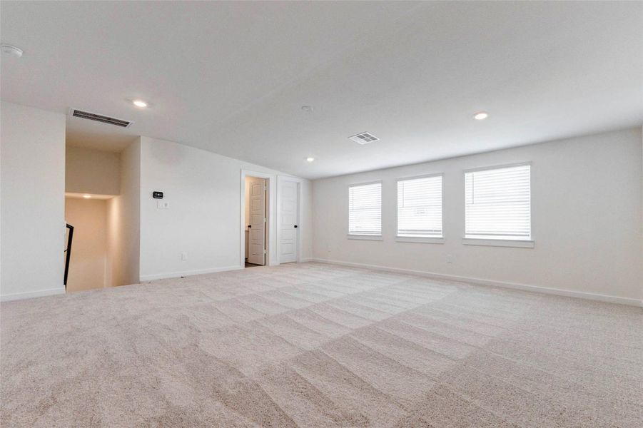 This expansive upstairs game room offers incredible flexibility for entertaining, relaxing, or creating the perfect media space. Plush carpeting and neutral tones provide comfort and versatility, while multiple windows bring in natural light, enhancing the bright, open feel. With ample space for a sectional, game tables, or a home theater setup, this room is ideal for gatherings, hobbies, or a private retreat away from the main living areas.