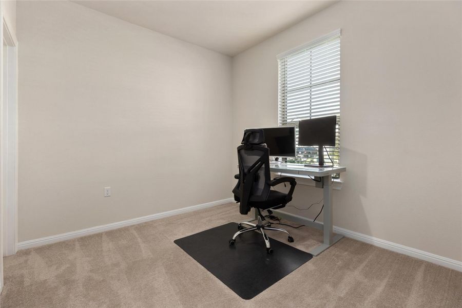 Office space with light colored carpet and baseboards