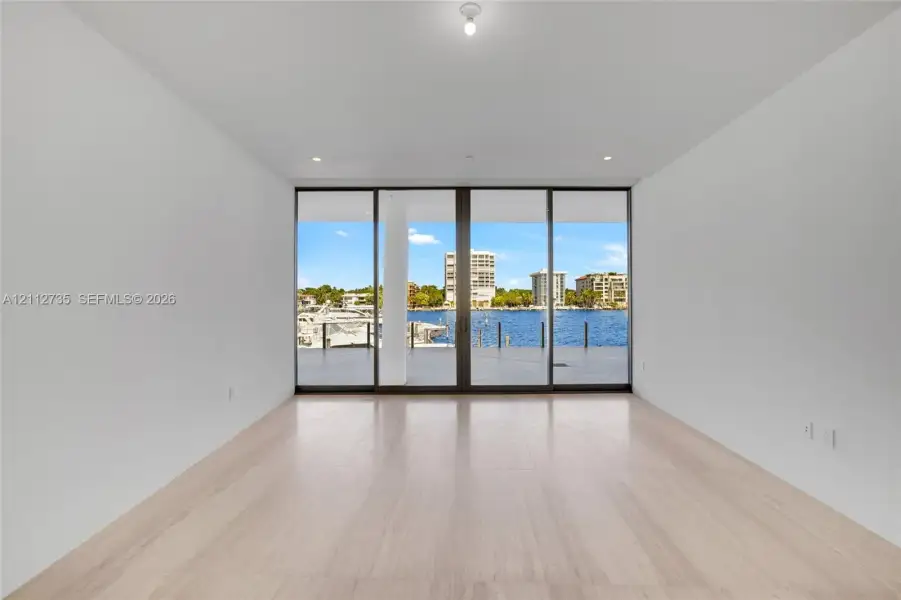 Floor-to-ceiling glass doors, neutral wood-finish flooring, recessed lighting, and outdoor terrace access
