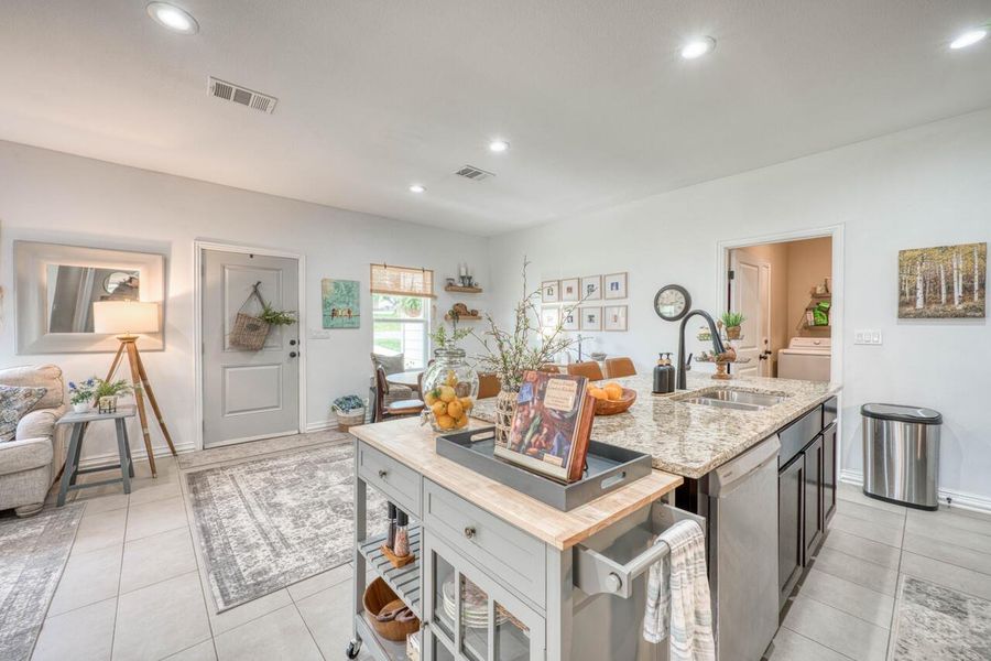 Kitchen island featuring a double-basin stainless steel sink, a gooseneck faucet, and granite countertops