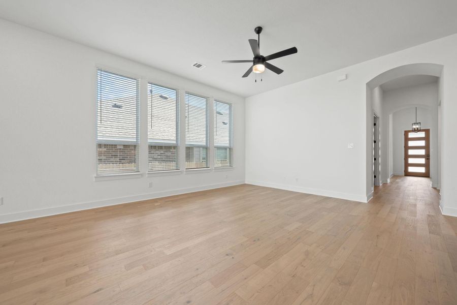 Empty room with healthy amount of natural light, arched walkways, and light wood-style flooring