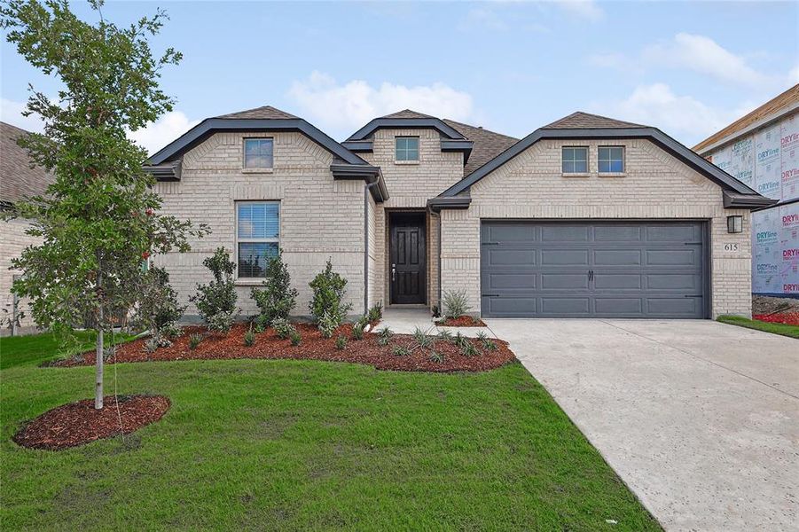 View of front of house with a garage and a front lawn