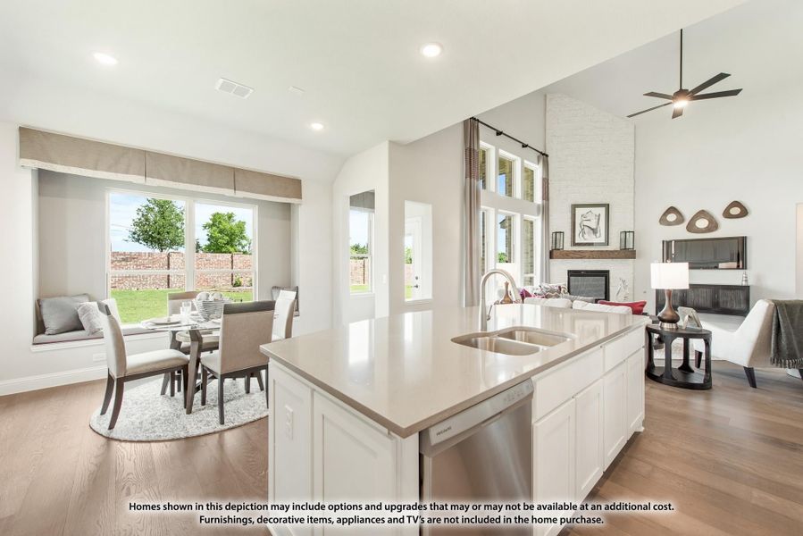 Open-concept kitchen with white island, flowing into dining area and living room with fireplace and high ceilings