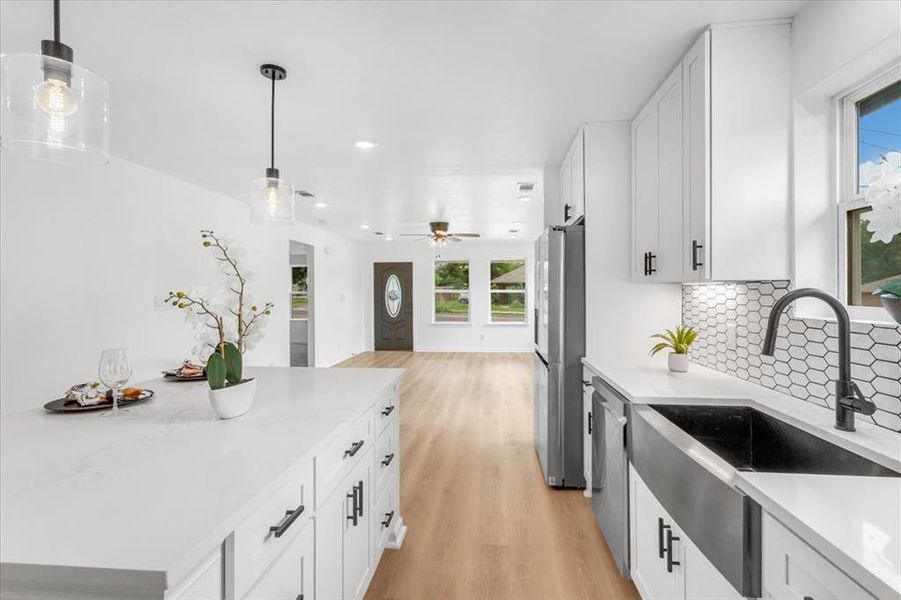 Kitchen with decorative backsplash, plenty of natural light, light wood flooring, and stainless steel appliances