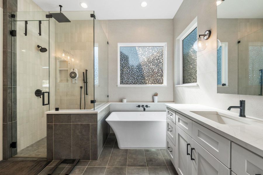 Full bathroom with a freestanding tub, vanity, a stall shower, dark tile patterned flooring, and recessed lighting