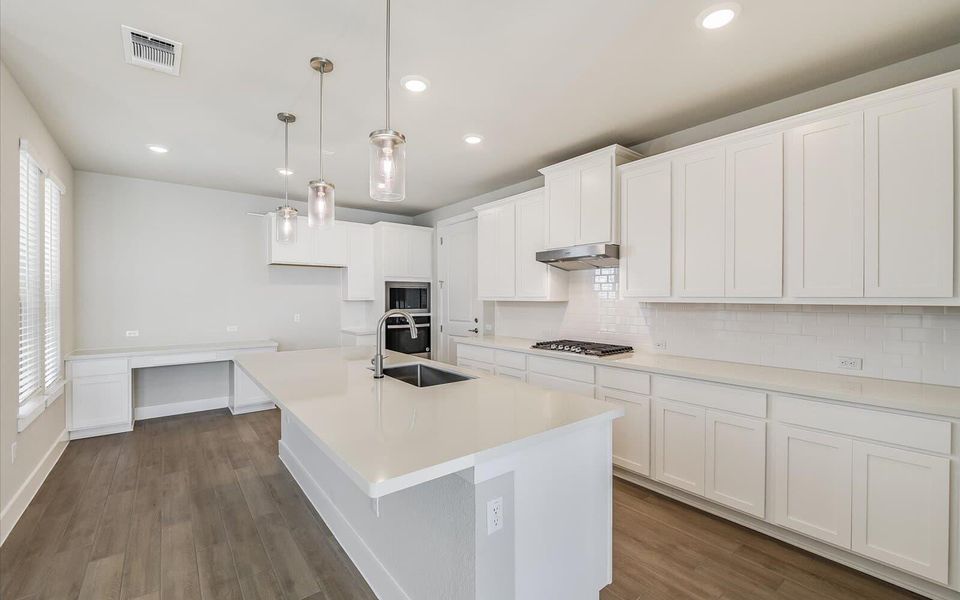 Kitchen with white cabinetry, an island with sink, dark wood-style floors, stainless steel appliances, and tasteful backsplash Kitchen with white cabinetry, an island with sink, dark wood-style floors, stainless steel appliances, and tasteful backsplash