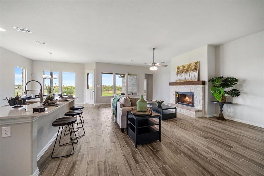 Living room featuring a fireplace, a ceiling fan, a chandelier, and light wood-style flooring Living room featuring a fireplace, a ceiling fan, a chandelier, and light wood-style flooring