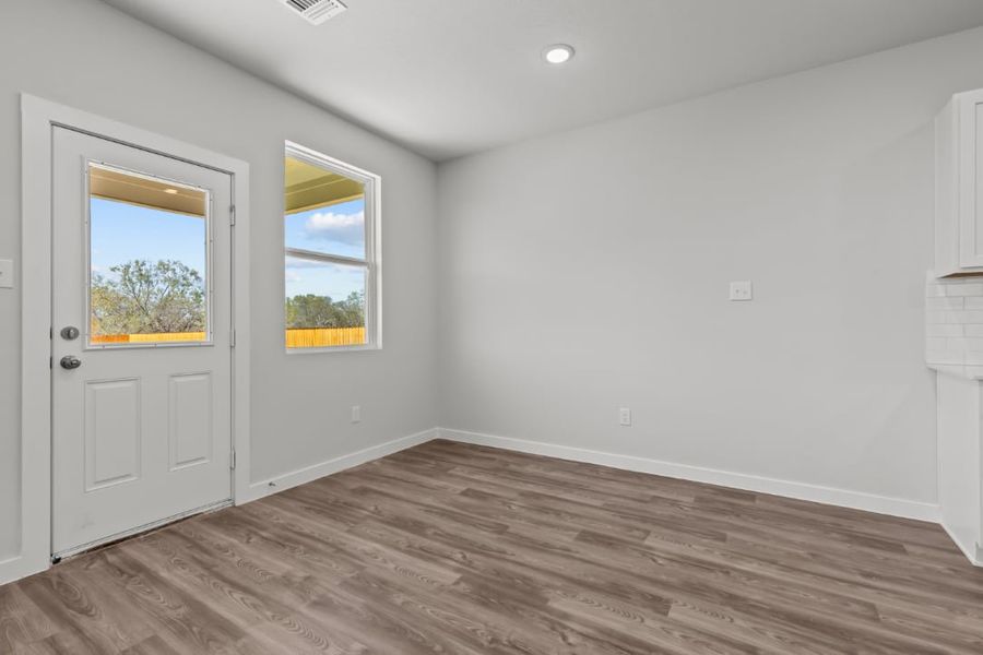 A room with white walls and a wood floor with a window.