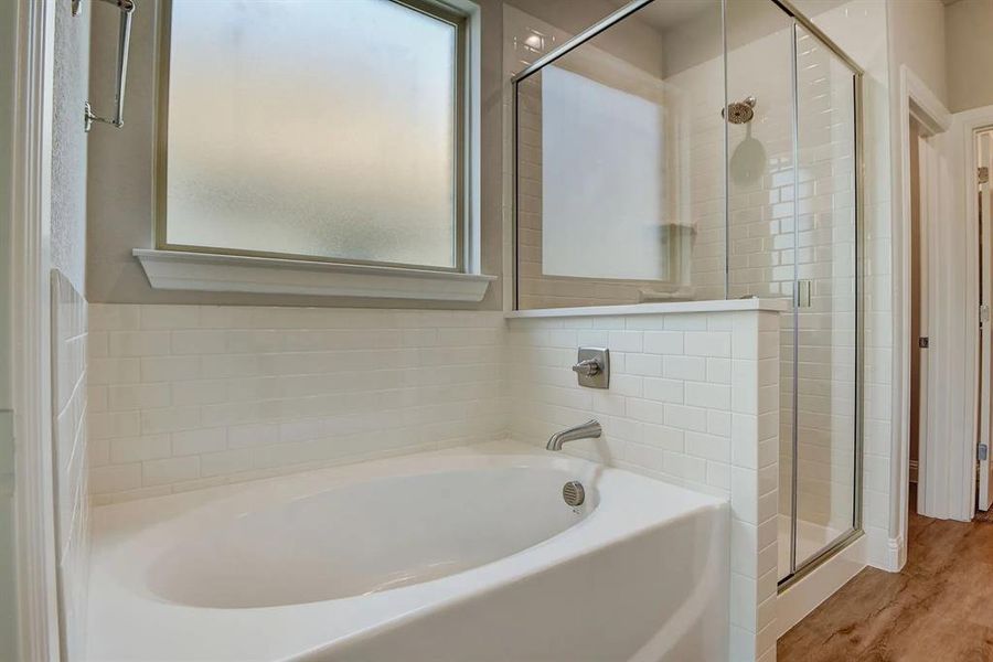 Bathroom featuring a bath, plenty of natural light, a stall shower, and wood finished floors