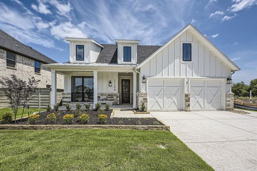 Modern farmhouse style home with board and batten siding, concrete driveway, and stone siding