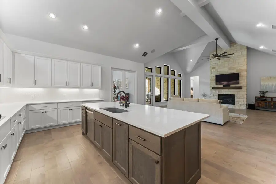 This photo provides a combined view of the kitchen and living room from the kitchen's perspective. It shows the seamless flow between the two spaces, with the large kitchen island in the foreground and the living room fireplace visible in the background. This photo provides a combined view of the kitchen and living room from the kitchen's perspective. It shows the seamless flow between the two spaces, with the large kitchen island in the foreground and the living room fireplace visible in the background.