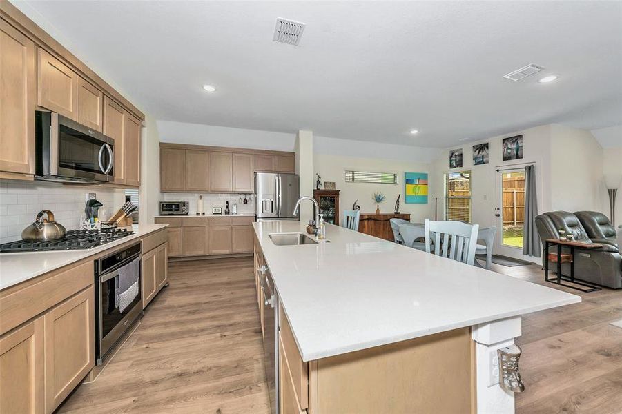 Kitchen featuring a kitchen island with sink, light wood-type flooring, stainless steel appliances, and sink