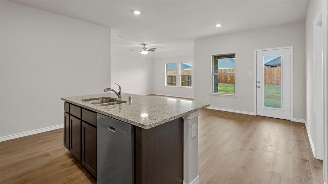 Kitchen island featuring a granite countertop, undermount stainless steel sink, and integrated dishwasher