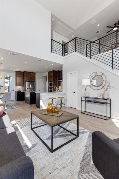 Living area featuring recessed lighting, ceiling fan, a towering ceiling, light wood-style floors, and a chandelier