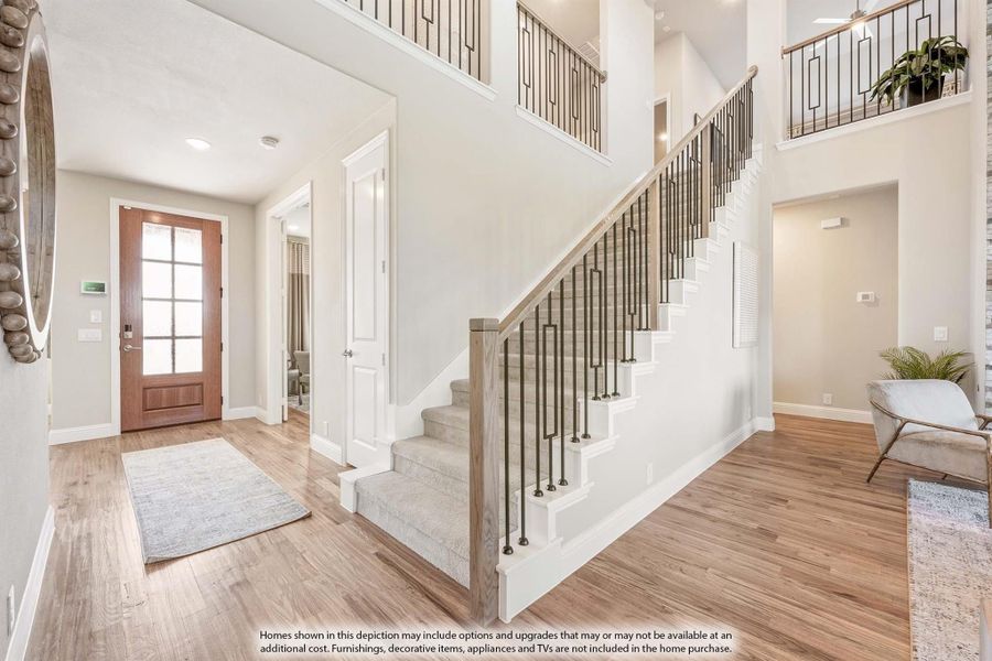 Two-story entryway with wood staircase, metal balusters, hardwood floors, and wood front door with glass panels Two-story entryway with wood staircase, metal balusters, hardwood floors, and wood front door with glass panels