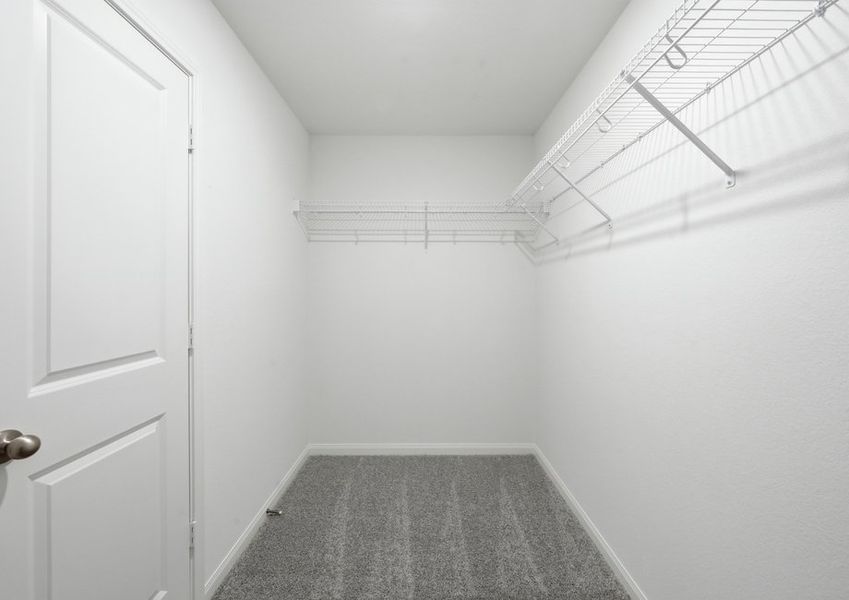 Primary walk-in closet featuring built-in wire shelving. Primary walk-in closet featuring built-in wire shelving.