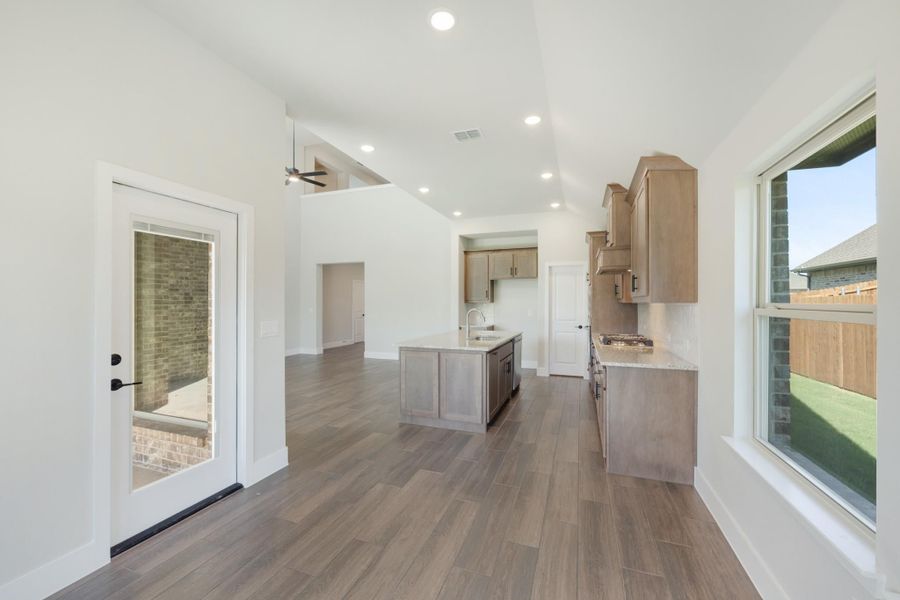 Open kitchen with center island, light wood cabinets, and wood-look tile floors Open kitchen with center island, light wood cabinets, and wood-look tile floors
