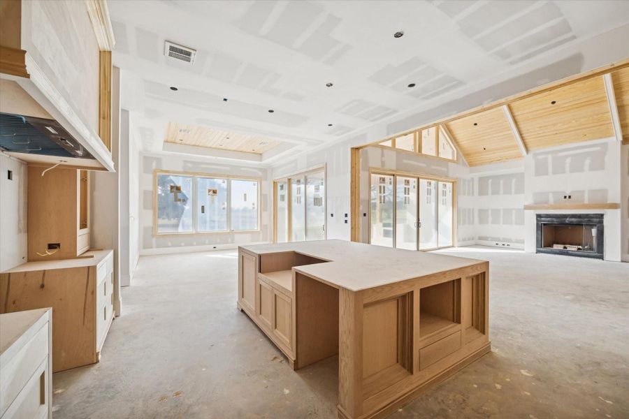 A broad look at the kitchen that showcases the oversized island, custom cabinetry, and future Thermador appliance suite. The slab countertops and full backsplash will add texture and luxury once installed. A central gathering place designed for cooking, hosting, and everyday living.