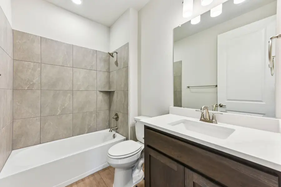 Full bath featuring washtub / shower combination, vanity, and light wood finished floors