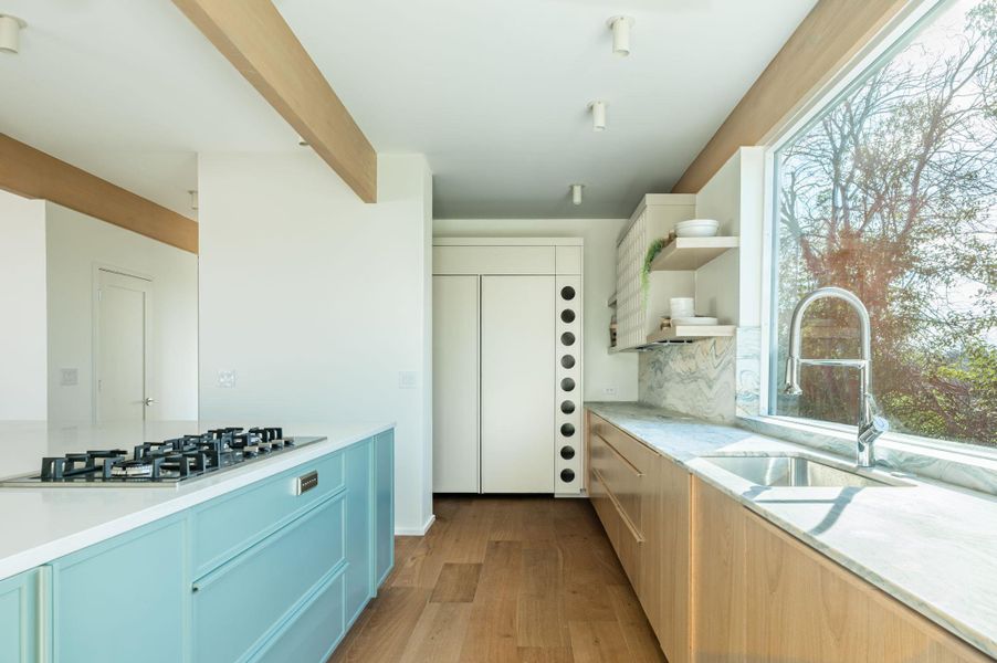 Dual tone kitchen featuring two tone cabinets, open shelves, light wood-type flooring, light stone counters, and stainless steel gas cooktop