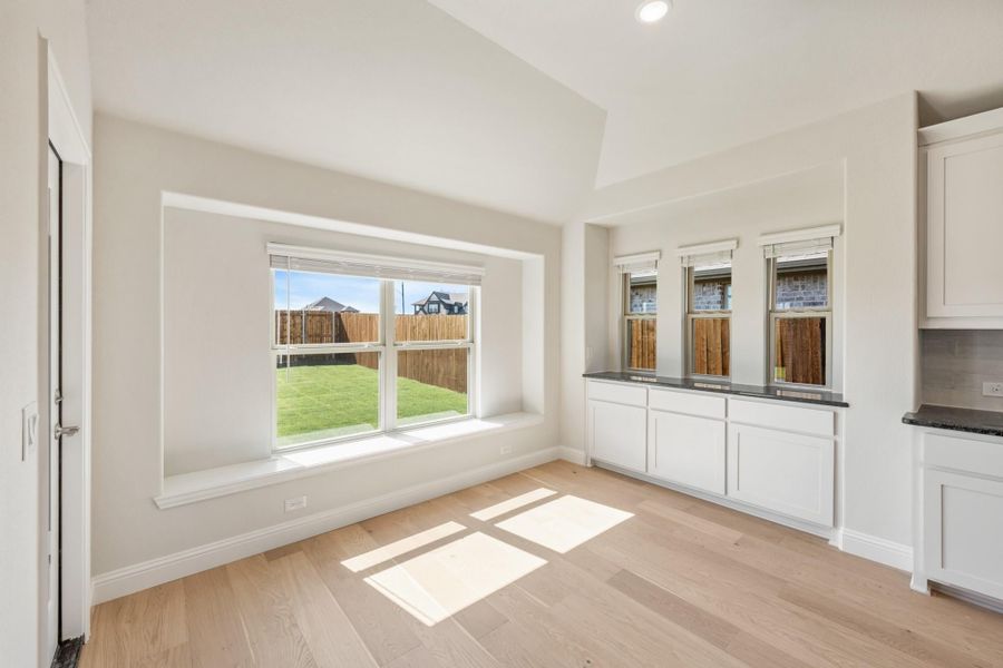 Bright dining area with hardwood floors, window seat, and white built-in cabinets with dark countertop Bright dining area with hardwood floors, window seat, and white built-in cabinets with dark countertop
