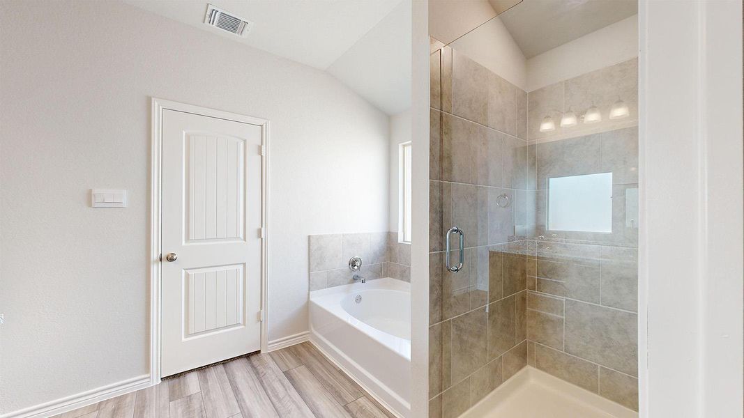 Bathroom featuring a shower stall, a garden tub, and light wood-type flooring Bathroom featuring a shower stall, a garden tub, and light wood-type flooring