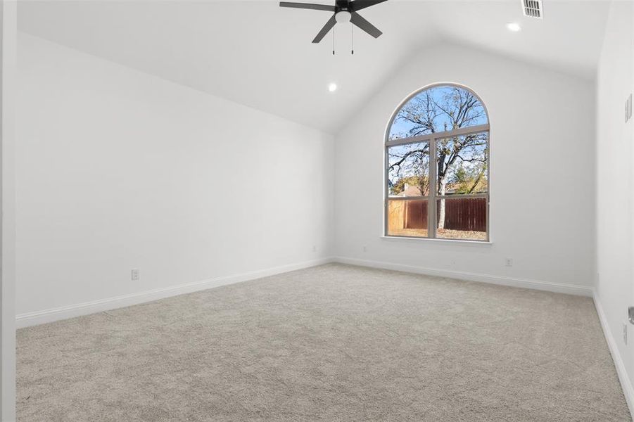 Carpeted spare room with vaulted ceiling and ceiling fan