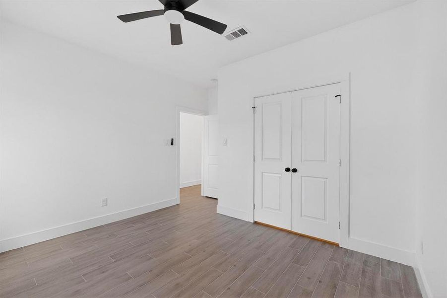 Unfurnished bedroom featuring wood finish floors, ceiling fan, and a closet