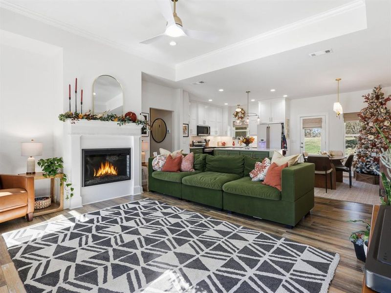 Living area featuring dark wood-style flooring, recessed lighting, a glass covered fireplace, a ceiling fan, and crown molding