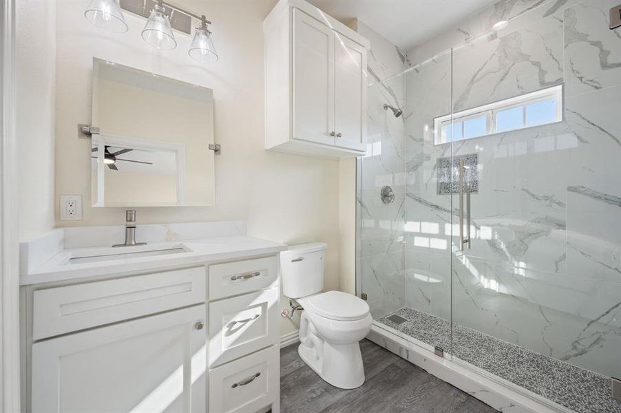Full bath featuring vanity, a marble finish shower, and dark wood finished floors Full bath featuring vanity, a marble finish shower, and dark wood finished floors
