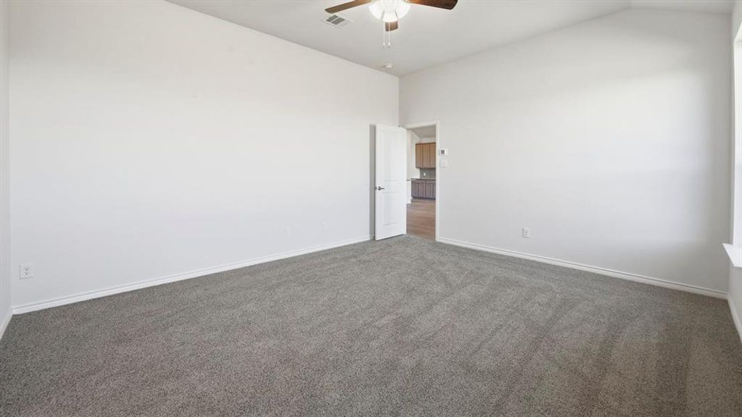 Carpeted spare room with a ceiling fan and lofted ceiling Carpeted spare room with a ceiling fan and lofted ceiling