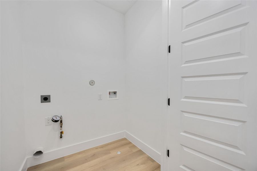 This dedicated 3rd floor  laundry room features convenient washer and dryer hookups, fresh white walls, and durable light-tone flooring, offering a clean and functional space ready for your preferred appliances.