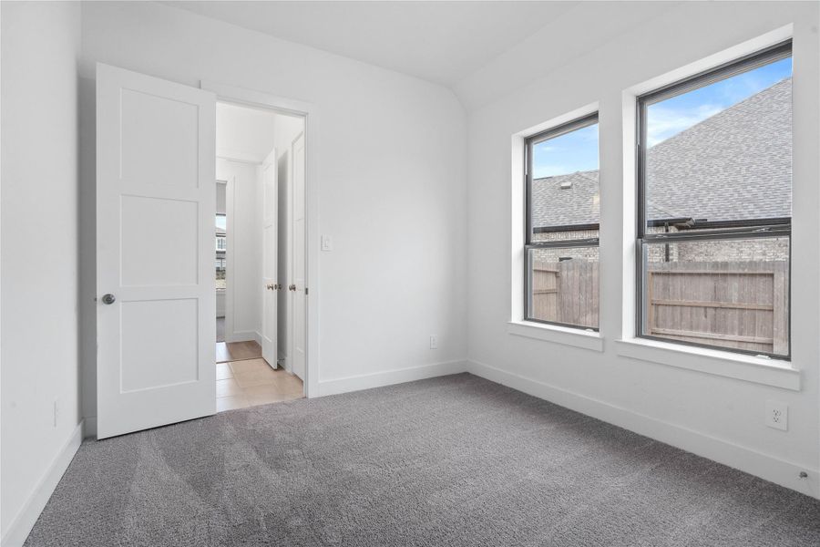 This secondary bedroom features plush carpet flooring, neutral tone walls, two large windows, an access door to a shared secondary bathroom.