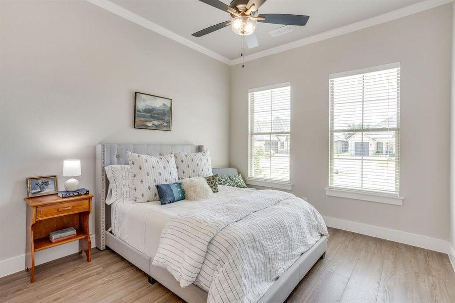 Bedroom 2 is Neutral-toned room featuring two large windows with blinds, wood-finish flooring, and a ceiling fan with integrated lighting