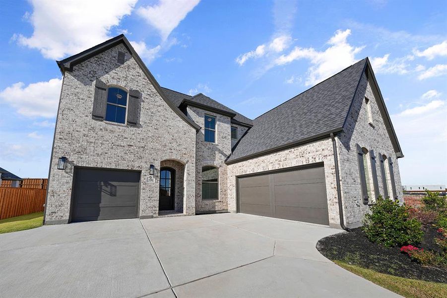 French country home featuring brick siding, concrete driveway, and a shingled roof