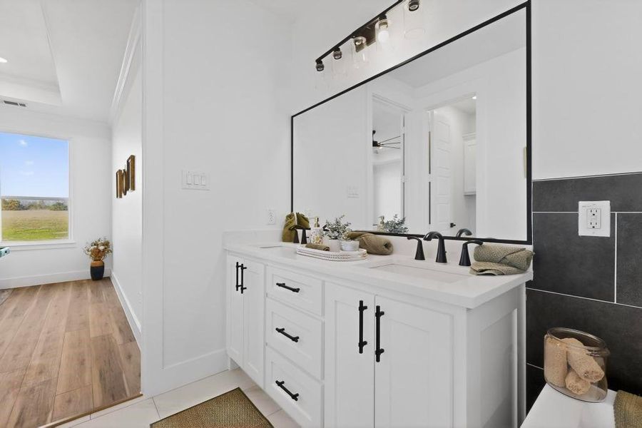Full bathroom featuring double vanity, light tile patterned floors, and ornamental molding Full bathroom featuring double vanity, light tile patterned floors, and ornamental molding