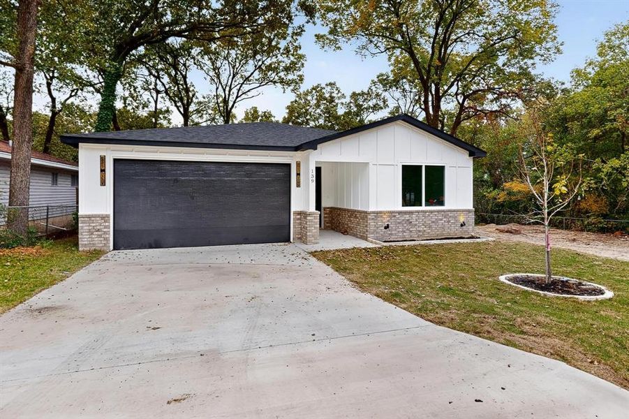 View of front of property featuring brick siding, driveway, board and batten siding, and an attached garage View of front of property featuring brick siding, driveway, board and batten siding, and an attached garage