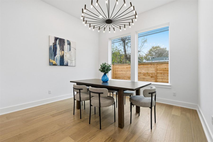 Bathed in natural light from dual picture windows, the dining room offers an inviting setting for gatherings. A modern chandelier provides a subtle statement, perfectly balancing warmth and sophistication.
