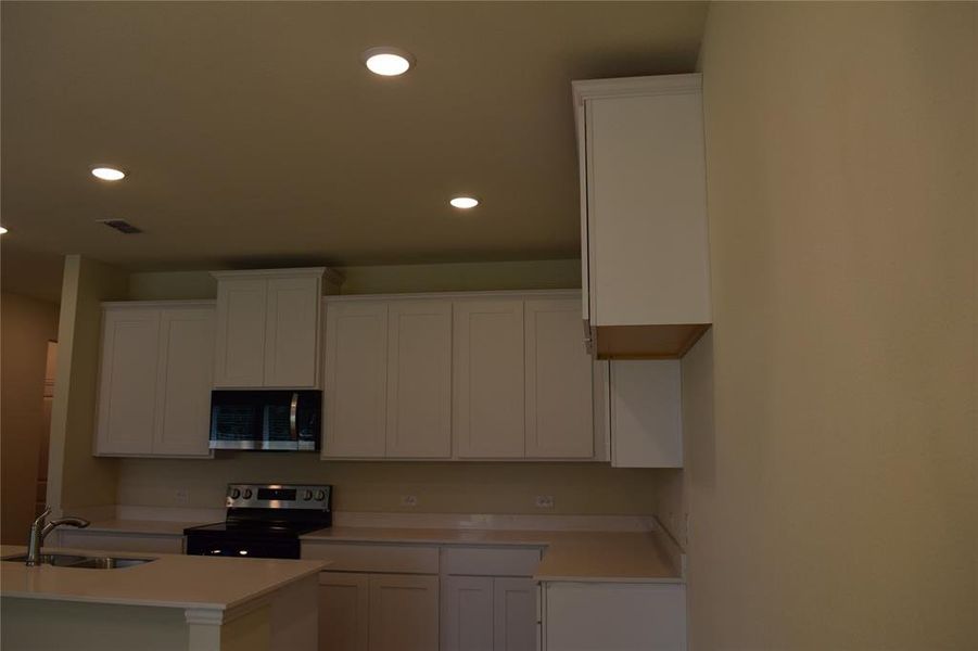 Kitchen featuring stainless steel appliances, a sink, recessed lighting, light countertops, and white cabinets